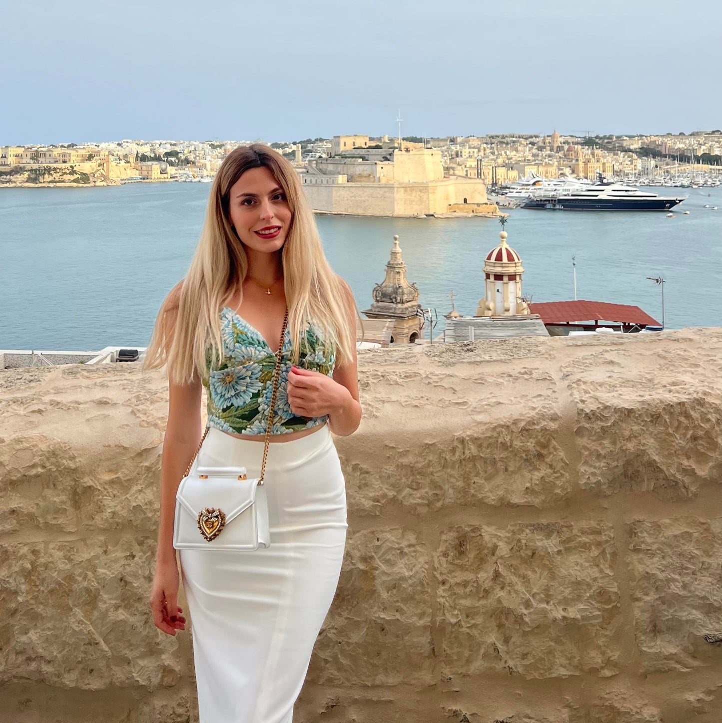 Woman posing in front of a scenic view with water and buildings in the background